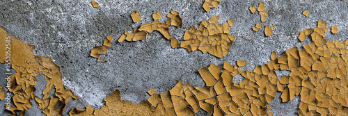 Peeling paint on the wall. Panorama of a concrete wall with old cracked flaking paint. Weathered rough painted surface with patterns of cracks and peeling. Wide panoramic texture for design background