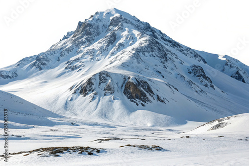 Towering peak covered in pristine white snow, casting long shadows across an expansive winter field.