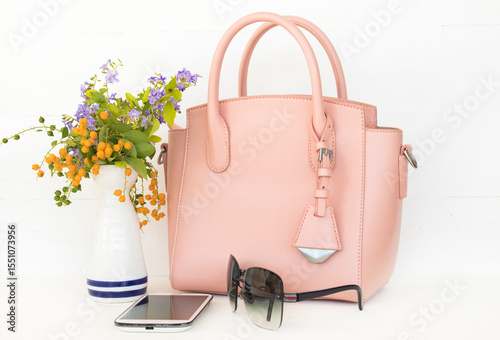 pink hand bag, mobile phone and sunglasses accessories of lifestyle woman arrangement flat lay style on background white
