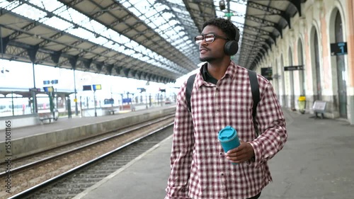 Young tourist walking in train station listening music