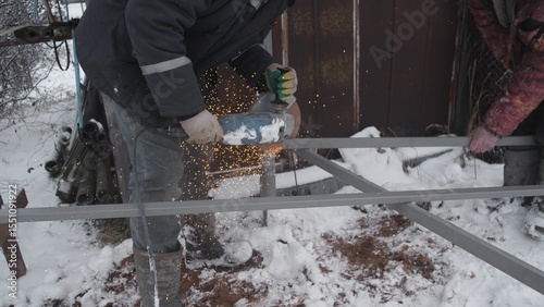 A skilled worker fabricates metal in harsh snowy conditions, showcasing expertise in winter metalworking