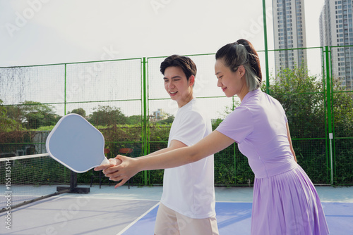 Couple practicing pickleball together on a sunny day in an urban setting