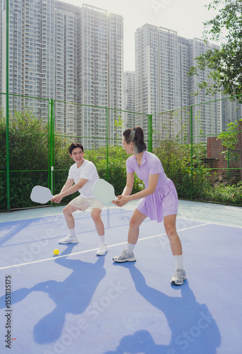Pickleball game between young players in urban setting on sunny day