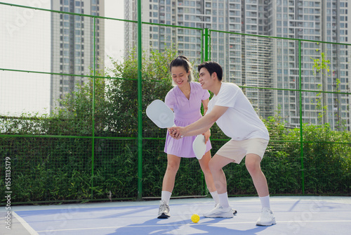 Friendly pickleball match between two young Asian players in an urban sports facility on a sunny day