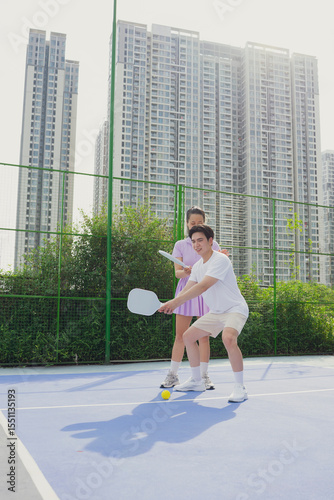 Engaging pickleball match between friends in an urban setting with tall buildings in the background