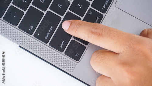 Top view of finger pressing shift button of a laptop keyboard isolated on white background