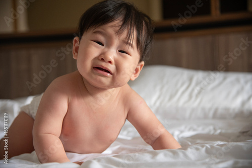 A crying Asian baby on the bed of six months has woken up and is calling for her mother