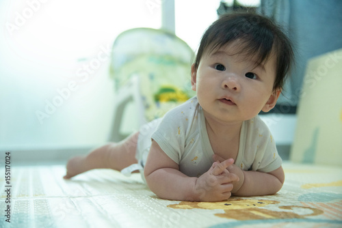 Adorable Baby laying on stomach developing neck control .tummy time for strengthen baby neck and shoulder muscles. Cute infant lying crawling on white bed happiness and fun. Tummy Time Concep