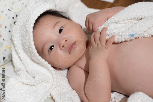 Asian adorable baby covered in a towel after bath time