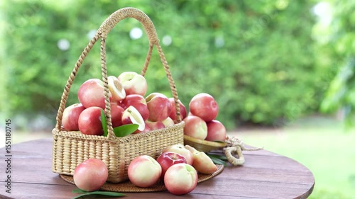 Shine Nectarine in basket on wooden table in garden, Shine Nectarine with leaves on blur background.