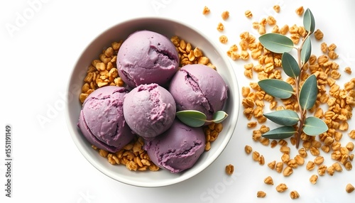 A close-up view of purple ice cream scoops in a bowl with granola and greenery.
