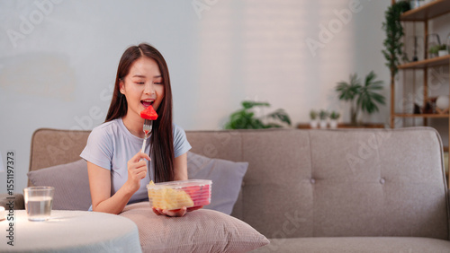 Young Asian woman embracing a longevity lifestyle by enjoying a nutritious fruit snack at home for optimal health and well being