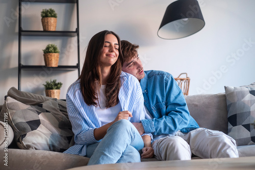 Young couple sitting on the sofa making peace after an argument. Reconnecting emotionally, sharing an intimate and honest moment of forgiveness, reconciliation and renewed love in a real-life relation