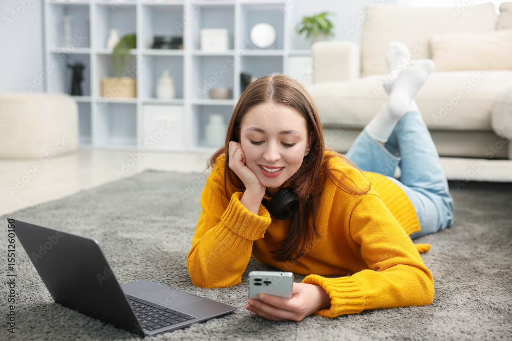© New Africa - Teenage girl with smartphone and laptop on floor at home