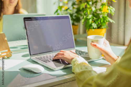 Cropped hands of businesswoman typing on laptop at office desk. Modern workplace, technology and professional lifestyle concept. Independent woman typing on laptop in coworking space.