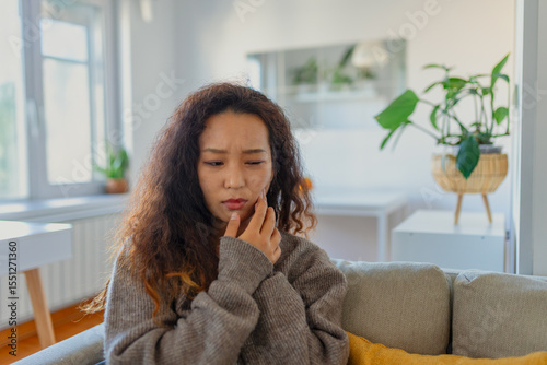 Portrait of unhappy young Asian woman suffering from toothache at home. Healthcare, dental health and problem concept.