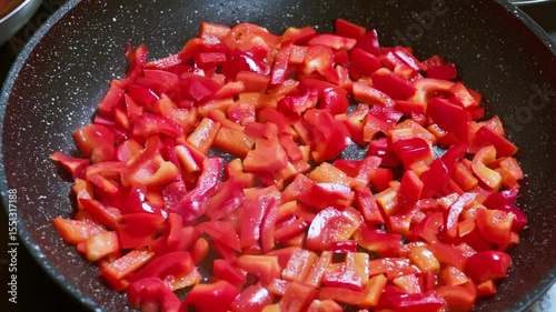 Adding salt to red bell peppers that are frying in a pan.