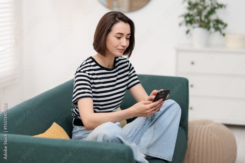 Obraz premium Woman using modern smartphone on sofa at home