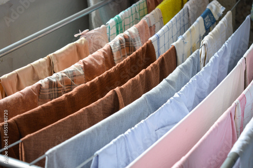 colorful clothes drying on metal rack indoors near window, symbol of home routine, laundry day, household chores, cleanliness, domestic life, family care, eco lifestyle
