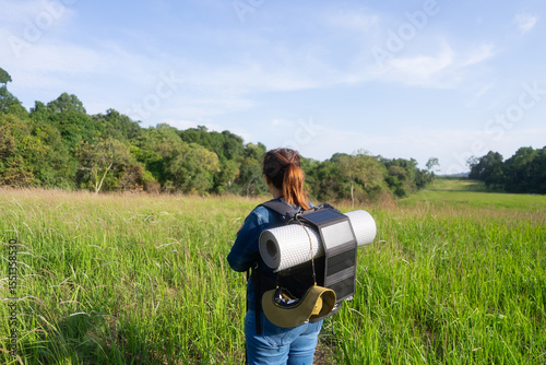 Eco-friendly hiking with solar-powered gear. Rear view of an Asian woman discovering sustainable travel, off-grid adventures, and nature exploration with low environmental impact.