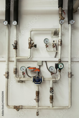 Water pipe with branch, water pressure meters and water meters on the wall of the house in the basement.