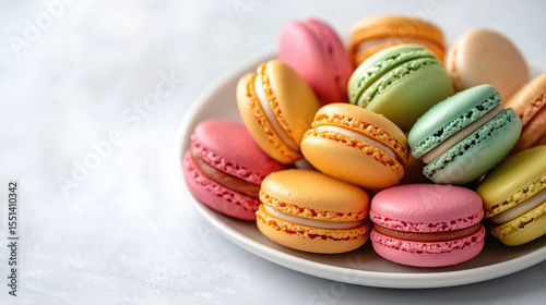 Colorful French macarons in pastel shades served on a white plate over light background. Sweet delicate dessert with creamy filling. Soft elegant composition.