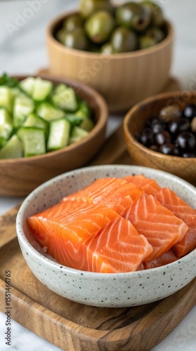 Fresh Salmon Fillets with Cucumber and Olives in Wooden Bowls on a Wooden Tray and Marble Background for Healthy Eating