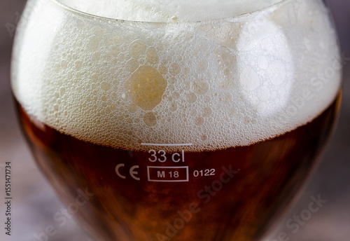 Close-up of glass of beer with foamy head. 33 cl measure. photo
