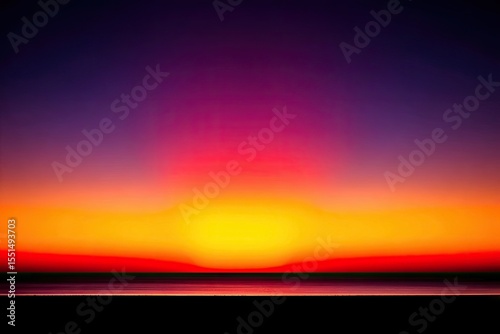 Blurry sunset over ocean. Vivid colors of orange, red, and purple blend in a soft, hazy horizon