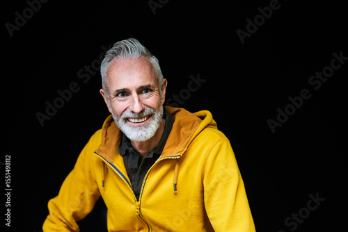 Cheerful mature man with gray hair against black background
