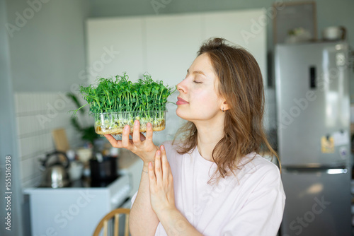 Woman enjoying the scent of microgreens in a kitchen setting