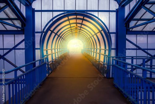 Blue tunnel with a light shining through it. The tunnel is empty and the light is coming from the top