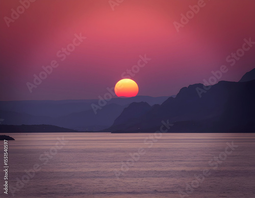 Vibrant sunset over mountain landscape and sea, dramatic pink and purple sky, scenic seascape with layered hills