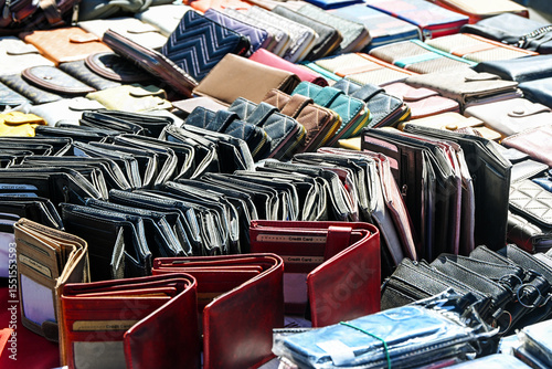 Lots of wallets and purses made of leather and other materials for sale at a flea market stall on a sunny day, copy space, selected focus