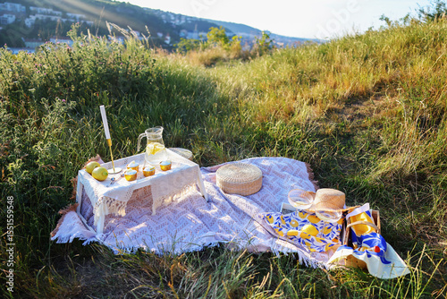 Boho summer picnic setup with cupcakes, lemonade, and cozy textiles in natural outdoor light