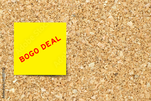 Yellow note paper with word bogo deal on cork board background with copy space