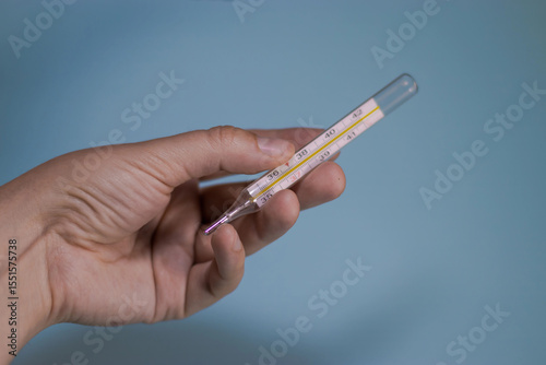 hand holding a thermometer on a blue background