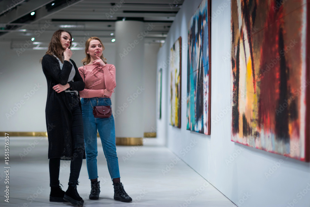 Fototapeta premium two girls discuss paintings in Gallery of modern art