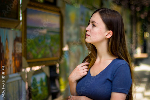 Beautiful girl examines paintings in the gallery