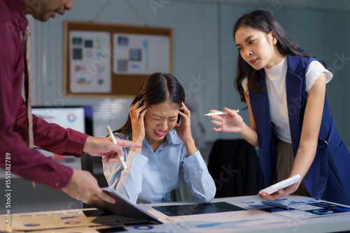 Asian businesspeople arguing with stressed businesswoman having headache during difficult meeting in office at night