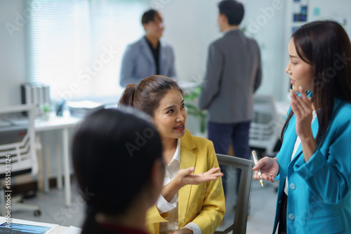 Asian businesswomen engaging in discussion and brainstorming during a meeting in a modern office environment, fostering collaboration and teamwork