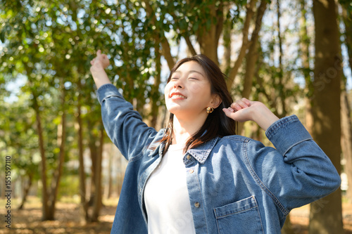 Photos 春の森林の中で両手を大きく開き明るい笑顔を見せる女性の開放的な姿