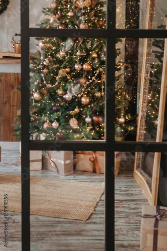 Home New Year's interior. Christmas tree with gifts, decorated with garlands in the kitchen. Cozy atmosphere of a home holiday, loft design of the room, Scandinavian style.