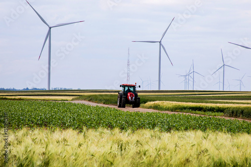 Rumbling tractor in lush green fields, sustainable agriculture whispers amid towering wind turbines, capturing Earth Day's eco-resonance