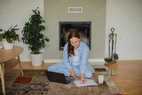 Wallpaper Mural mage of a pretty woman working on her laptop while sitting comfortably on the floor at home. Concept of remote work, freelance lifestyle, casual productivity, and modern home office. Torontodigital.ca