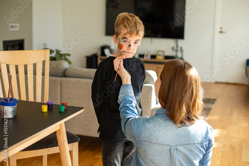 Wallpaper Mural Festive Halloween makeup at home. Mother applying fun face paint to her cheerful little son while preparing for Halloween.  Torontodigital.ca