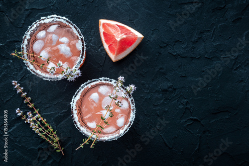 Salty Dog cocktail with fresh grapefruit juice, lime juice, and thyme, overhead flat lay shot on black with copy space