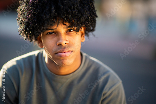 Latin young man with curly hair gazing calmly at the camera