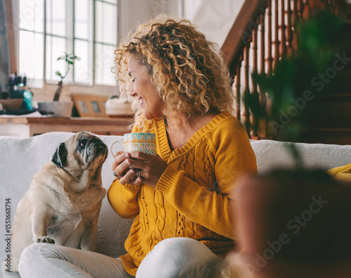 Happy woman relaxing at home on the sofa with her beloved dog by her side. A warm, joyful moment of affection, comfort and emotional well-being through the simple presence of a loving pet