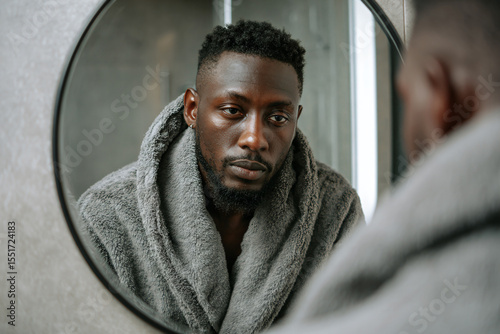a man in a robe is looking at himself in a mirror